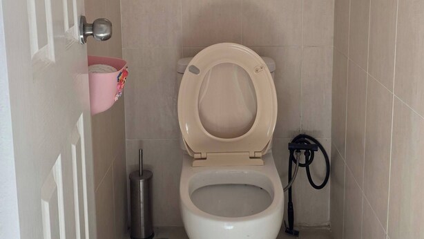 A small bathroom with a toilet, a hand sanitizer dispenser, and a window. - Room-cozy Room Near Airport (Perth)