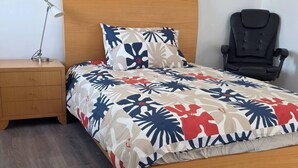 A bed with a floral bedspread, a wooden headboard, a nightstand with a lamp, and a black chair. - Room-cozy Room Near Airport (Perth)