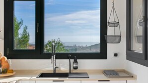 A kitchen with a large window, a sink, and a hanging basket.