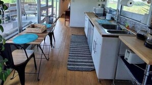Cozinha moderna com área de refeições, janelas amplas e vista para o exterior.