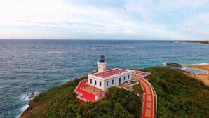 Ein Leuchtturm auf einer Klippe mit einem roten Weg, der dorthin führt, mit Blick auf den Ozean.