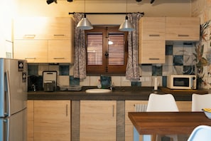A kitchen with wooden cabinets, a microwave, a toaster, and a sink. - Paphos Traditional Holiday House (Mesa Chorio)