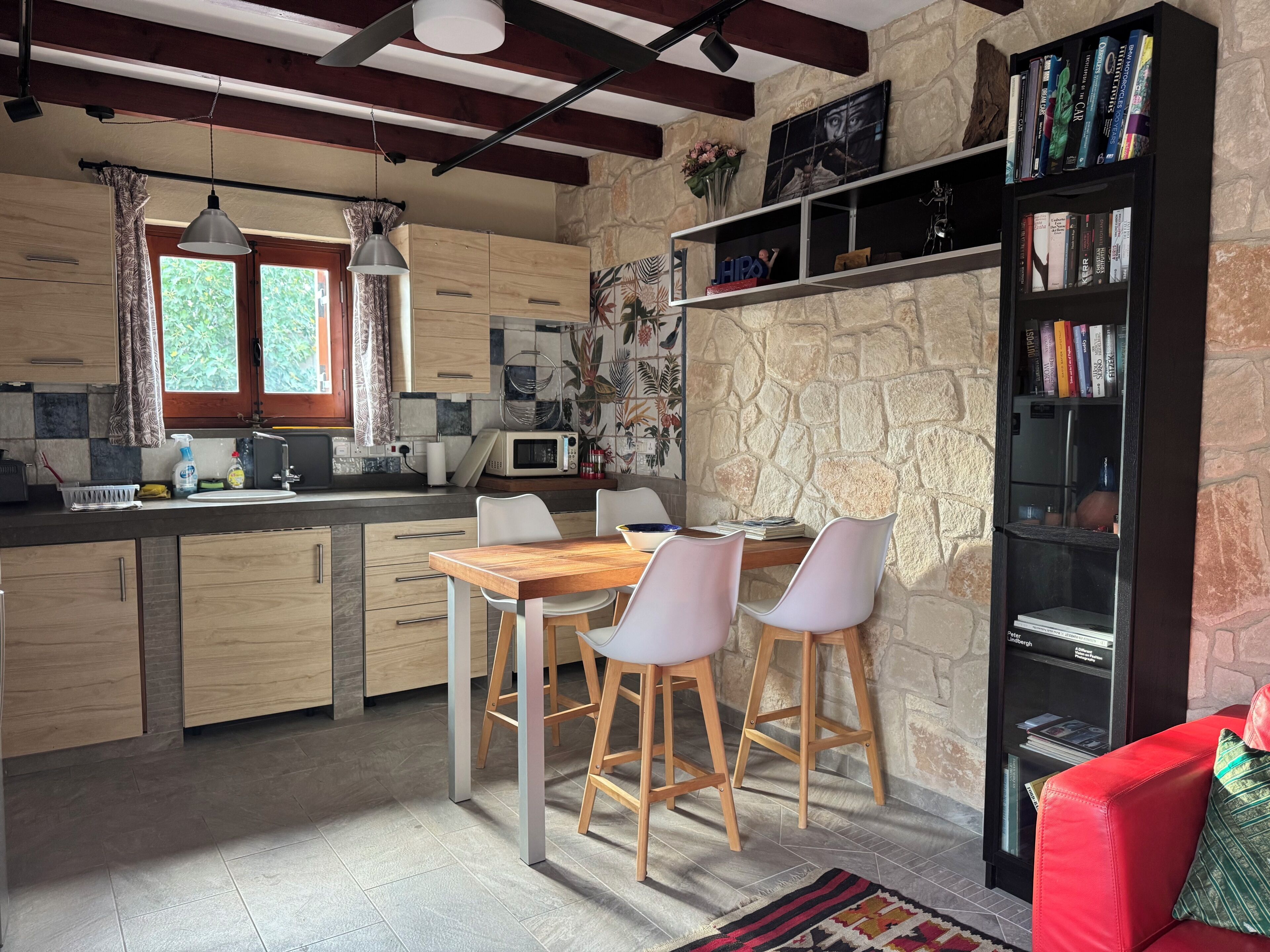 A kitchen with a dining area, a bookshelf, and a red couch.