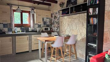 A kitchen with a dining area, a bookshelf, and a red couch.