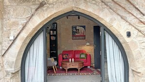 Een kamer met stenen muren, een rode bank, een houten bijzettafeltje en een boekenkast.