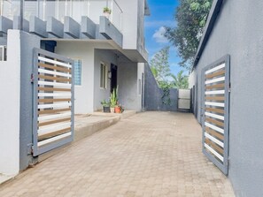 Um edifício moderno com um pátio pavimentado, portões de metal e plantas em vasos.