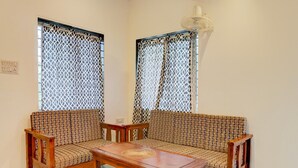 Une pièce avec deux canapés à motifs, une table basse en bois et un ventilateur de plafond.
