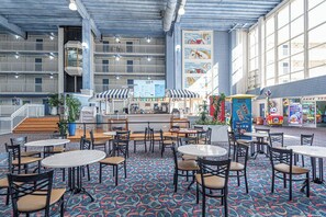 Amplio espacio interior con varias mesas y sillas, un mostrador de servicio de alimentos y una zona de juegos para niños.