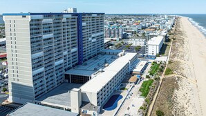 Ett högt hotell med flera våningar, ett parkeringsgarage och utsikt över stranden.