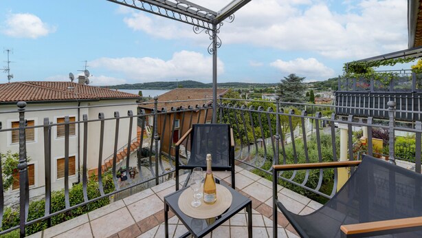 Un balcone con tavolo, sedie e una bottiglia di champagne.