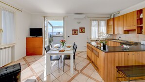Cucina con zona pranzo, TV e vista attraverso una porta aperta.