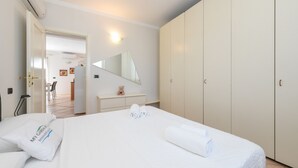 Una camera d'albergo con un letto, un armadio, uno specchio, una scrivania e una sedia.