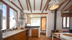 A compact kitchen with wooden cabinets, a sink, and a dining area with a table and chairs.