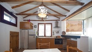 A kitchen with wooden cabinets, a white table, and a hanging light fixture.