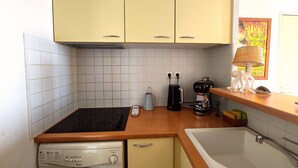 Une cuisine compacte équipée d’un lave-linge, d’une machine à café et d’un évier.