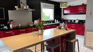 Una cocina moderna con armarios rojos, una isla central y un ventanal que proporciona luz natural.