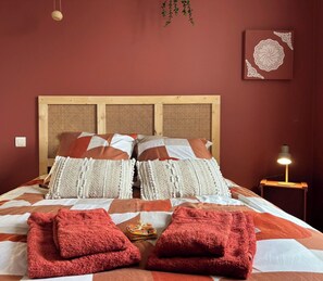A bed with a wooden headboard, multiple pillows, and two red towels on the bed.