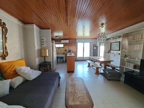 A room with a wooden ceiling, a bed, a desk, a bench, a bookshelf, and a kitchen area. - Apartment 150m from the beach - 6 guests (Argelès-sur-Mer)