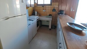 Una cucina compatta con frigorifero, fornello, lavandino e una finestra sopra il bancone.