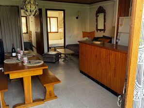 A dining area with a wooden table, benches, and a bar counter. - Apartment 150m from the beach - 6 guests (Argelès-sur-Mer)