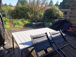 An outdoor patio with a table and chairs, surrounded by greenery and a barbecue grill. - Quiet house in sought-after area - 4 guests (Quend)