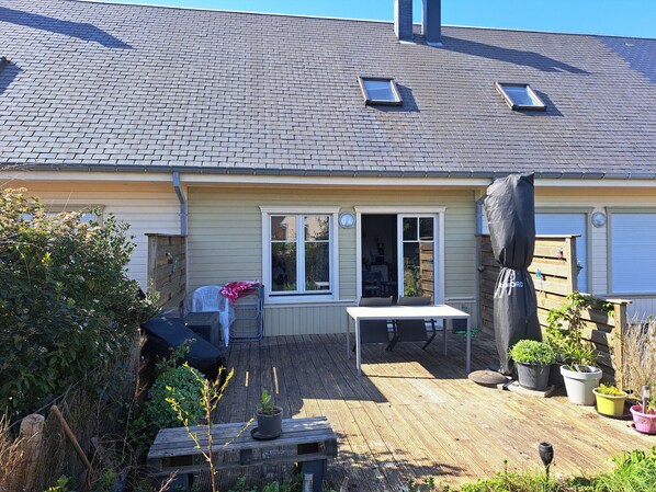 A house with a brick roof, a covered patio with a table and chairs, and a garden area with potted plants. - Quiet house in sought-after area - 4 guests (Quend)