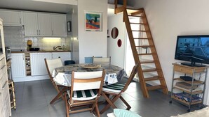 A compact living space with a kitchen, dining area, and a TV on a wooden stand. - House with parking - 4 guests (Bretignolles-sur-Mer)