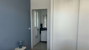 Ett sovrum med en säng, ett sängbord, en spegel och en dörr som leder till ett badrum.