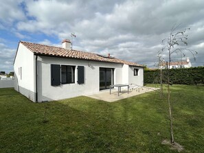 Ein modernes Einfamilienhaus mit Ziegeldach, kleiner Terrasse und gepflegtem Rasen.