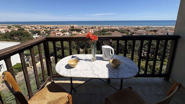 Ein Balkon mit Tisch, Stühlen und einer Vase mit Blumen.