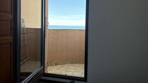 Ein Balkon mit Blick auf das Meer, ein Fliesenboden und eine Holztür.