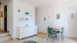 A modern kitchen with white cabinets, a dining table with chairs, and a small round table with a blue surface. - Cozy pavilion with parking - 4 guests (Gruissan)