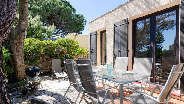 An outdoor patio with a table and chairs, a grill, and a stone wall. - Cozy pavilion with parking - 4 guests (Gruissan)