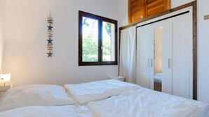 A bedroom with a bed, a window, a wardrobe, and a wall decoration. - Cozy pavilion with parking - 4 guests (Gruissan)