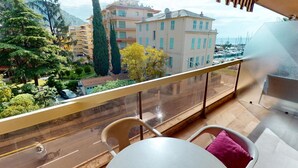 A balcony with a view of a road, buildings, and trees. - Studio with terrace - sea view, pool (Menton)