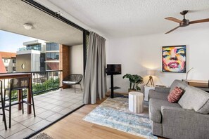 Uma sala de estar moderna com varanda, televisão de tela plana, sofá, mesa de jantar e ventilador de teto.