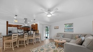 Una cocina moderna con comedor, una sala de estar con sofá y un ventilador de techo.