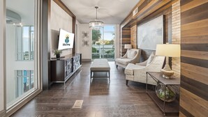 A spacious living area with a sofa, a coffee table, a TV, and a wooden accent wall.