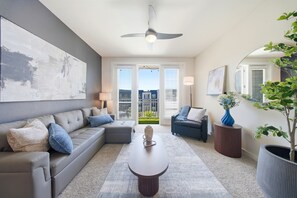 Un salon moderne avec un canapé gris, une table basse et un ventilateur de plafond.