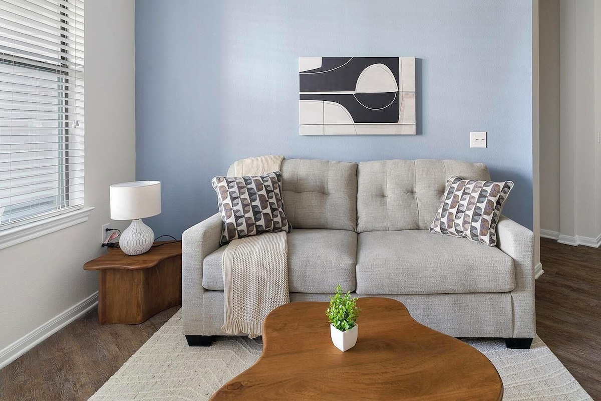A living room with a sofa, a coffee table, a lamp, and a painting on the wall.