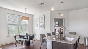 A modern kitchen with a granite countertop, stainless steel sink, and pendant lighting. - Landing Apartments near Gateway Crossing (McCordsville)