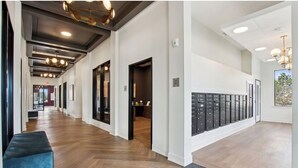 A spacious hallway with wooden flooring, a blue bench, and a row of lockers. - Landing Apartments near Gateway Crossing (McCordsville)