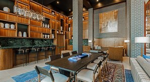 A modern interior with a wooden bookshelf, a marble countertop, a dining table with chairs, and a patterned rug.