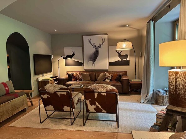 A modern living room with a sofa, chairs, a coffee table, and artwork on the walls. - Modern Garden Chalet APT With SPA and Pool (Château-d’Œx)