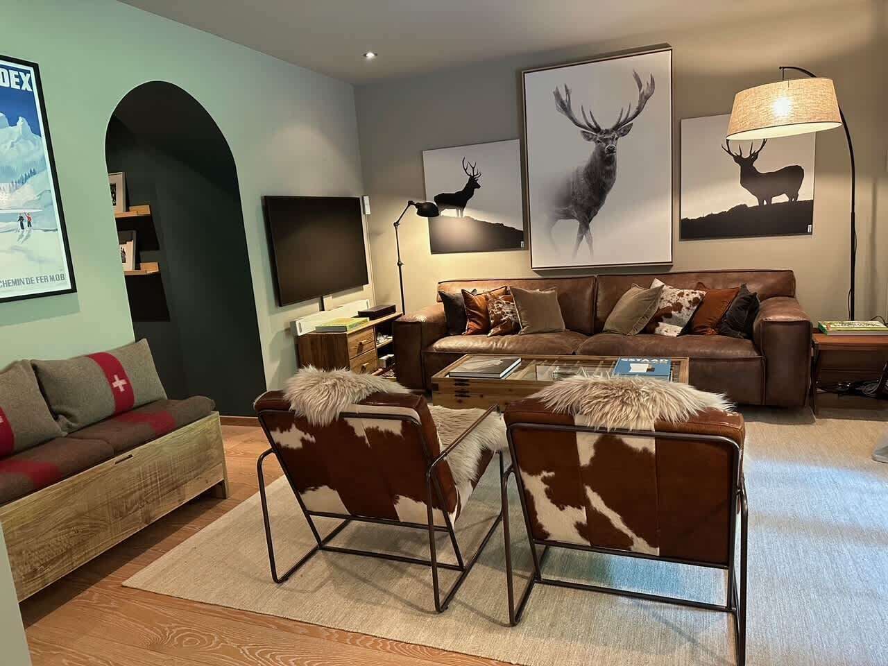A cozy living room with a sofa, two chairs, a coffee table, and artwork on the walls.