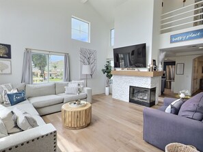 Ein modernes Wohnzimmer mit Kamin, Fernseher und Sofa.