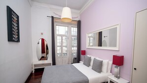 Ein Schlafzimmer mit einem Bett, Nachttischlampen, einem Spiegel, einem Fenster und einer Tür.