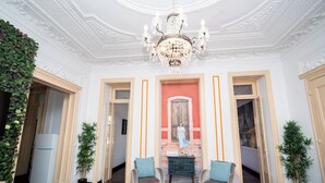 Ein Zimmer mit einer Chandelüster, zwei Sesseln, einem kleinen Tisch und einem Kamin.