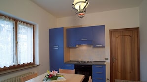 Una cocina compacta con armarios azules, una estufa a gas y una mesa de comedor de madera con sillas.