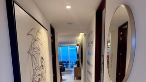 A modern hotel hallway with a large abstract painting, circular mirrors, and a view to a balcony area. - Oceana Luxury Escape | 3BR/3BA | Ocean Views (Bucerias)